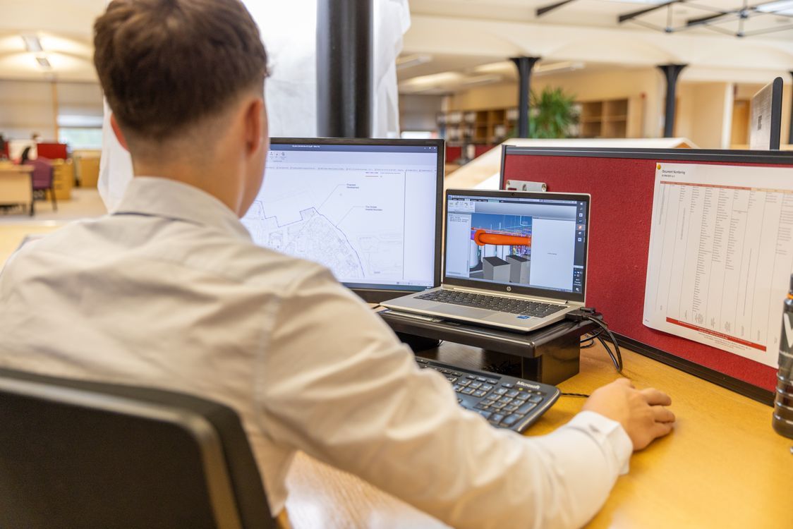 Engineer reviewing a 3D CAD display concept on computer monitors